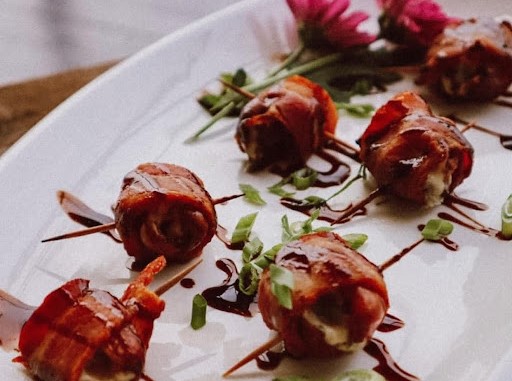 Bacon-wrapped Medjool dates stuffed with blue cheese, served as an appetizer.
