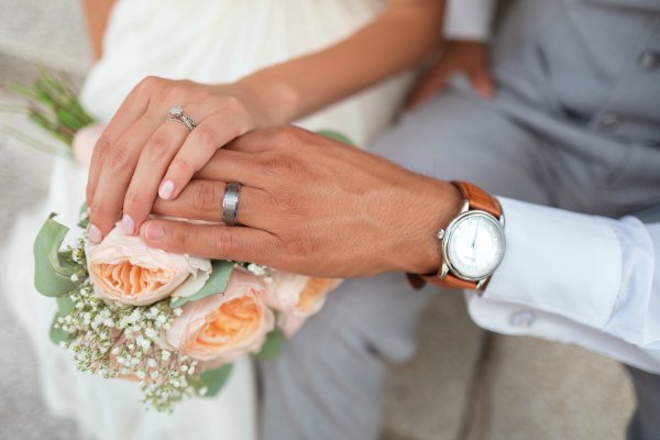 A close-up shot of the bride’s and bridegroom’s hands on a wedding bouquet.
